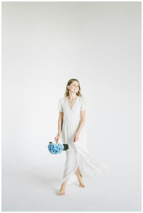 Elegant woman in white dress holding a blue hydran