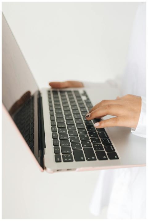 Close-up view of hands using a laptop keyboard. Id