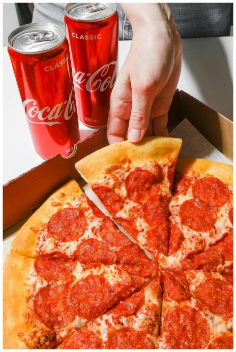 Close-up of pepperoni pizza with two cans of cola,