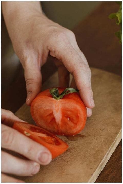 Detailed close-up of hands slicing a fresh tomato
