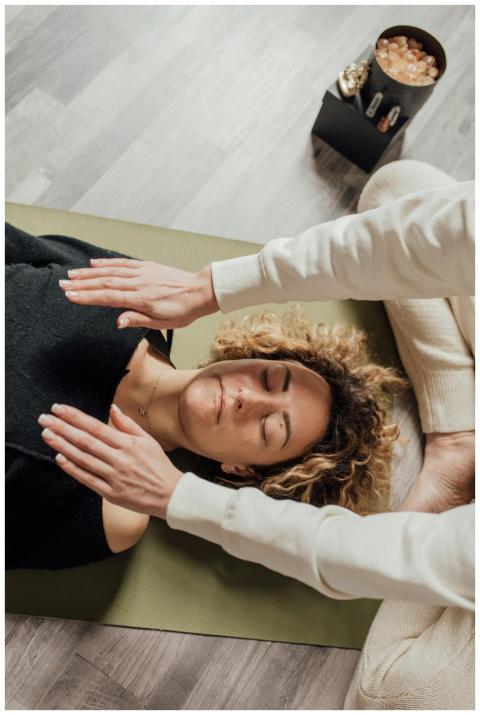 A woman receiving Reiki therapy with hands hoverin