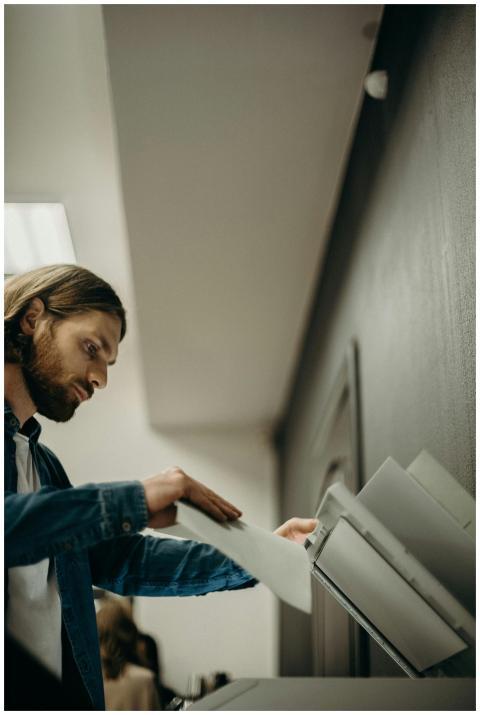A man operates a printer in a modern office settin