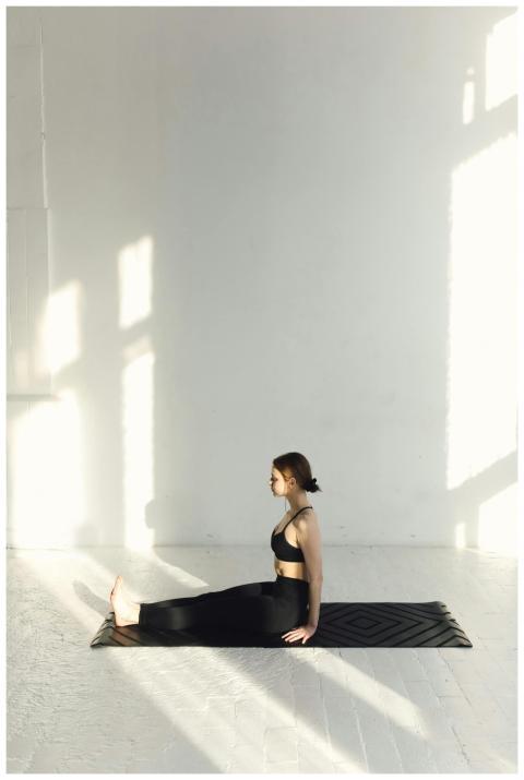 A woman performs yoga exercises in a sunlit indoor