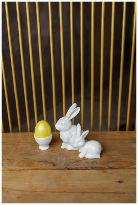 Porcelain rabbits beside a yellow Easter egg in an