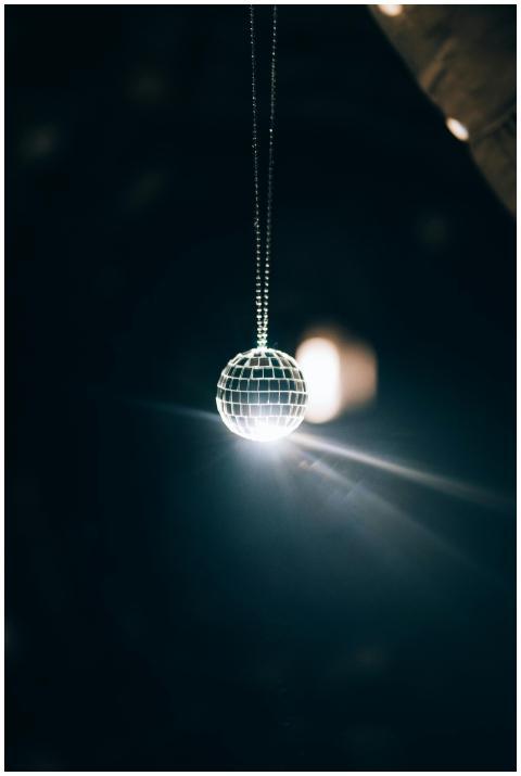 A glowing mirror ball hanging in a dark room, refl