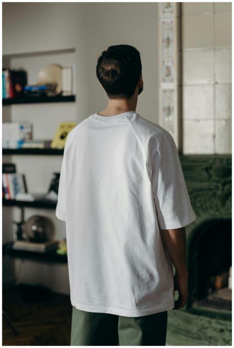 Adult male wearing a white t-shirt stands indoors
