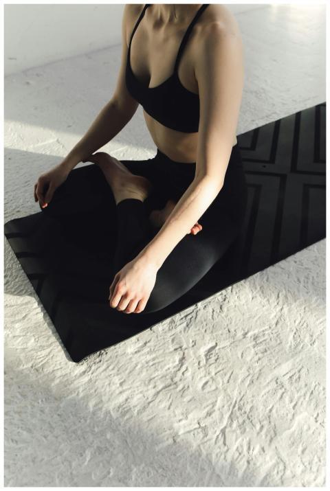Person sitting in a yoga pose on a mat, embracing