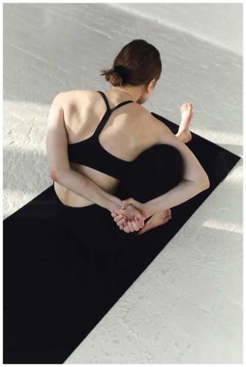 A woman in black activewear practicing yoga on a m