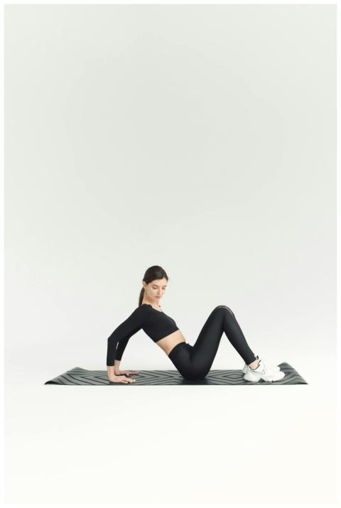 Fit young woman doing yoga exercise on mat in mini