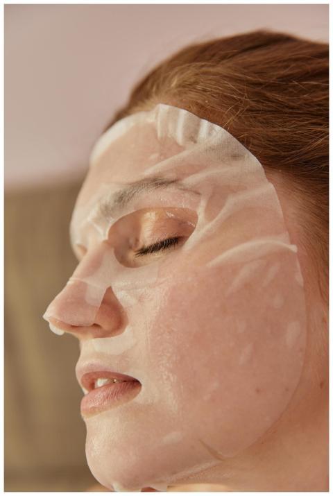 A woman peacefully relaxing with a hydrating facia