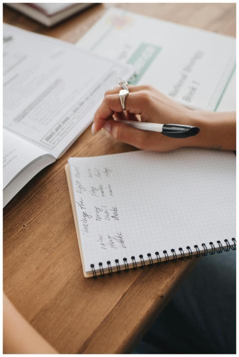 A person takes notes in a notebook, emphasizing st