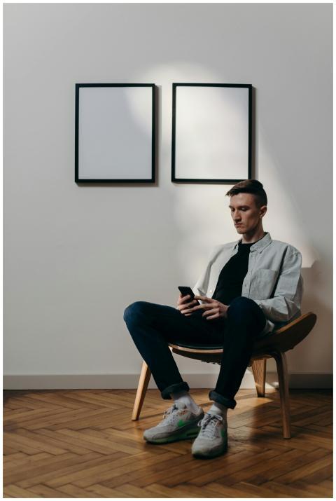 A man using a smartphone in a minimalist home offi