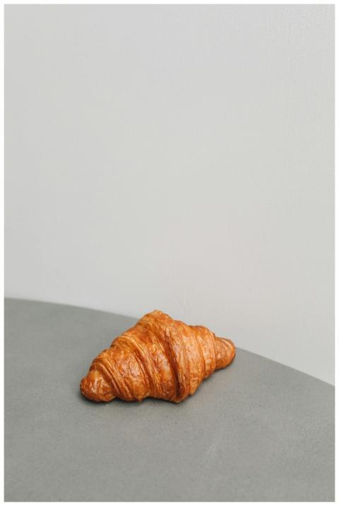 Golden croissant elegantly placed on a gray surfac