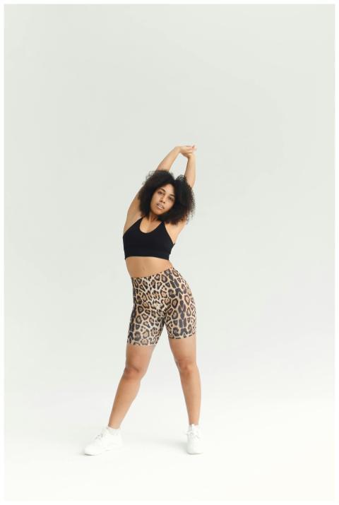 Fit woman stretching in studio wearing leopard pri