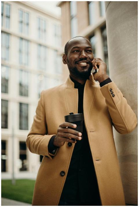 Smiling businessman in a trench coat holding a cof