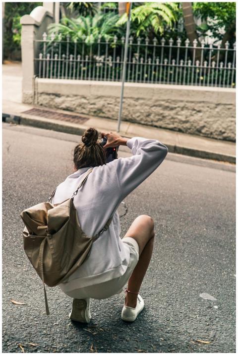 Woman with backpack photographing an urban scene o