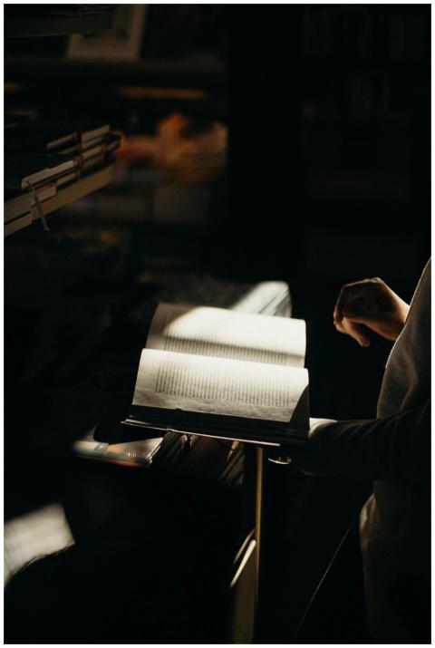 A dimly lit scene of a person reading an open book