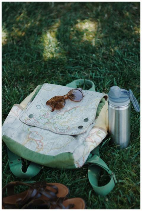 Close-up of backpack, sunglasses, and thermos on g