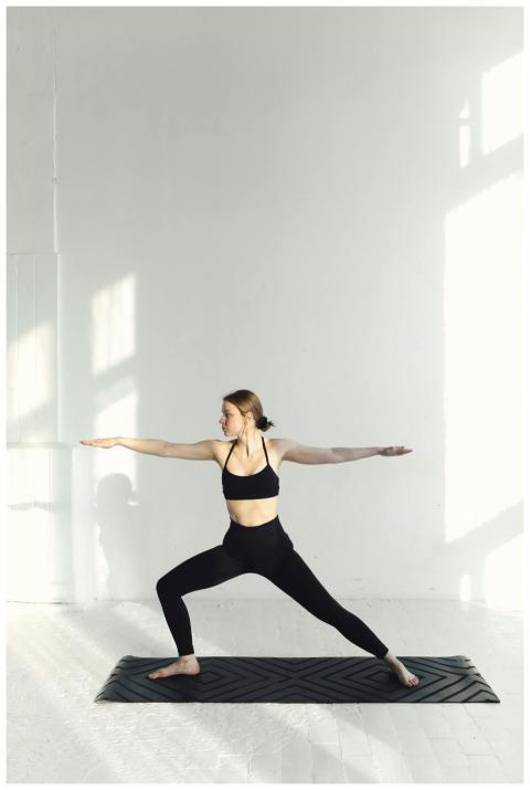 A woman performing a yoga pose in a bright, minima