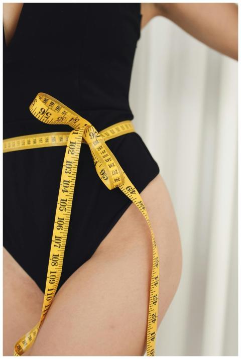 Close-up of a woman measuring her waist with a yel