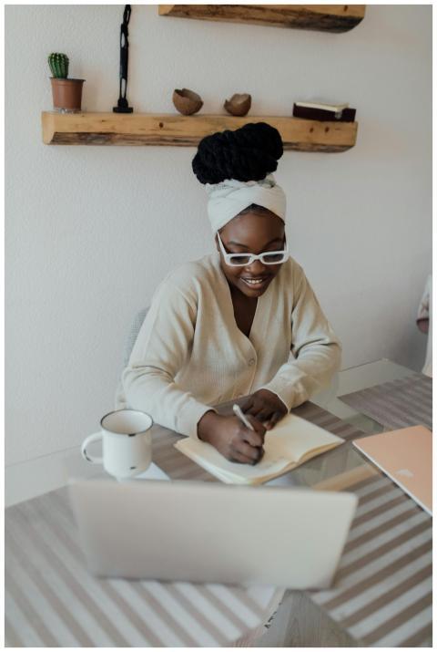 African American woman sitting indoors writing in