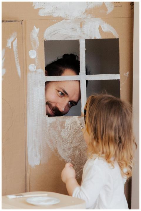 Father and child enjoy creative play with a cardbo