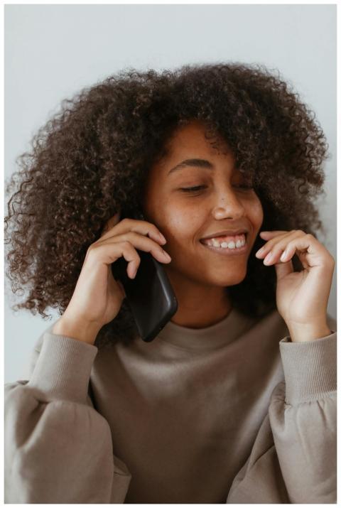 Smiling woman with afro hair enjoying a phone call