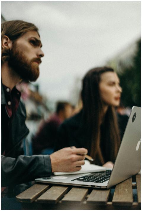 Portrait of young adults using laptops outdoors, f