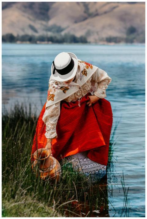 A woman in traditional Peruvian attire gathers wat
