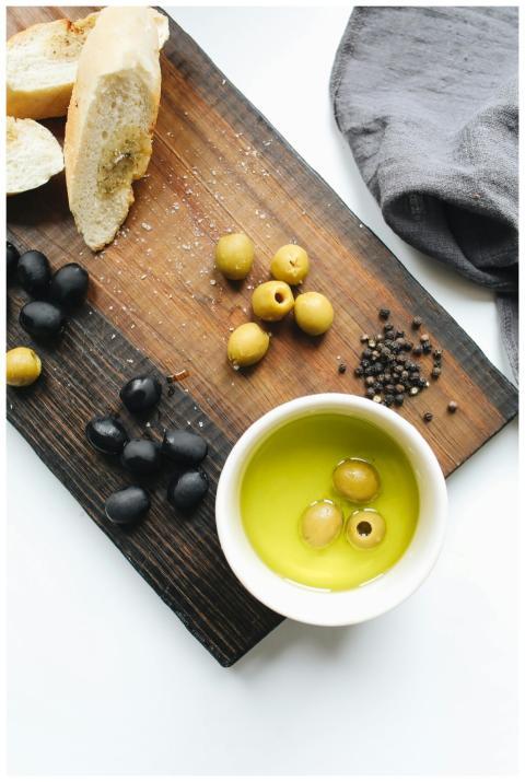Rustic wooden board with fresh olives, bread, and