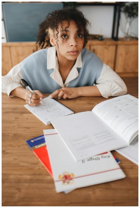 Focused young woman studying at a desk with open b