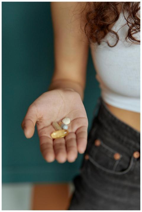 Person's hand holding different pills, highlightin