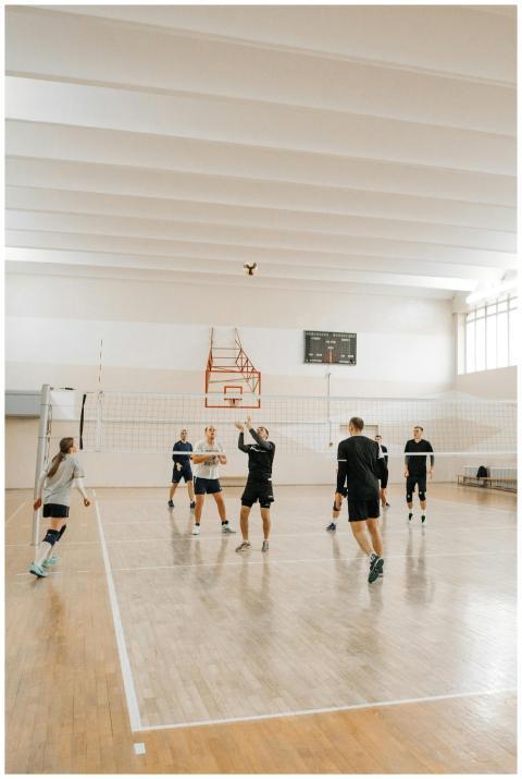 Team of adults playing volleyball indoors, showcas