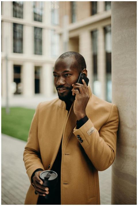 Elegant man in a trench coat talking on a smartpho