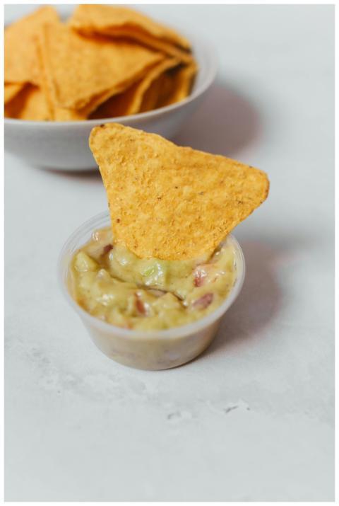 Close-up of crunchy tortilla chip with creamy guac