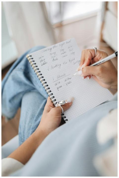 Close-up of a woman writing thoughts in a spiral n