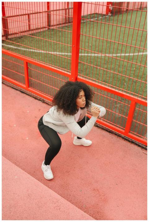 Woman performing squats on a vibrant red sports tr