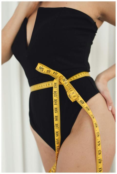 Close-up of a woman measuring her waist with a yel