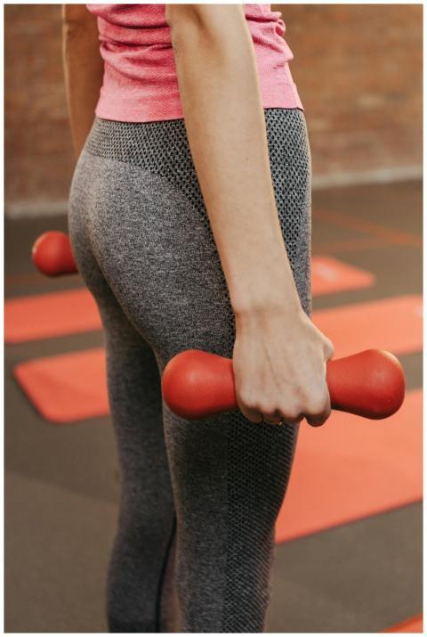 Fitness woman holds dumbbells during workout in gy