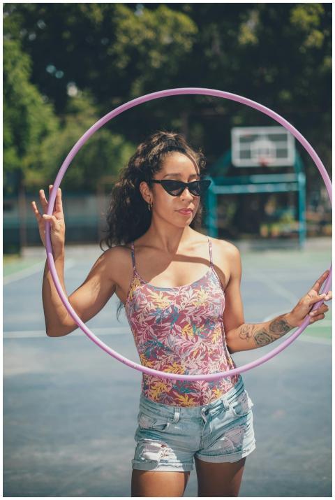 Young woman in sunglasses performing with a hula h