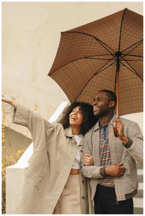 Happy couple smiling and holding an umbrella, enjo