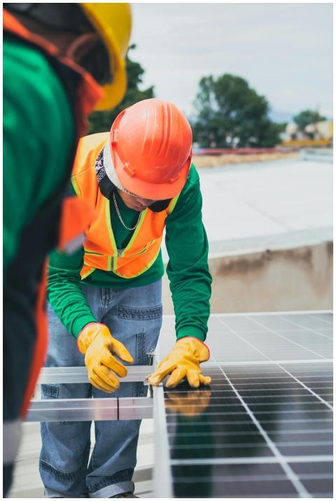 Worker in safety gear installing solar panels on a