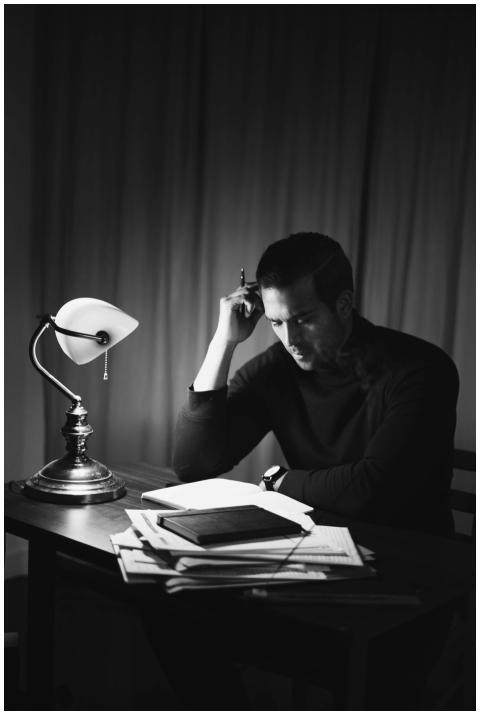 Black and white of concentrated male with pen doin