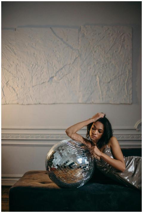 Stylish woman in silver dress posing with disco ba