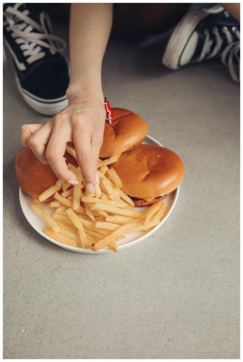 Close-up shot of a hand grabbing fries from a plat