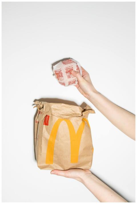 A person holding a McDonald's burger and paper bag