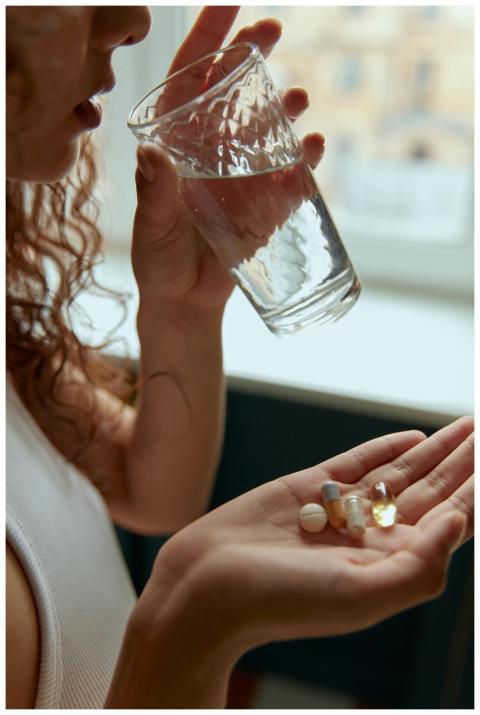 Close-up of a woman holding pills and a glass of w