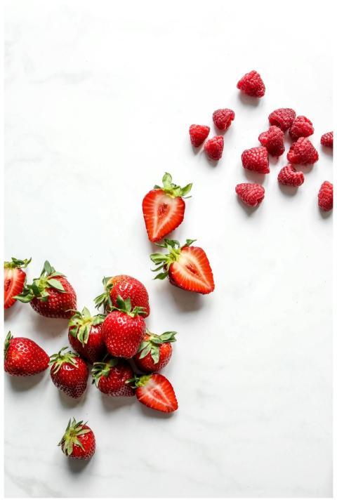 Vibrant strawberries and raspberries on a white ma