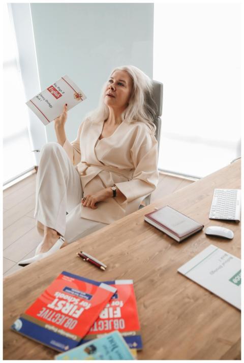 Woman in light robe sitting at desk with books, ap