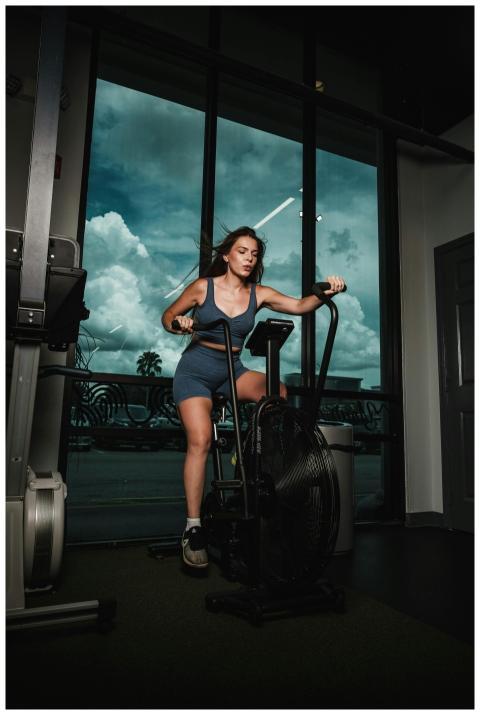 A woman works out on a stationary bike indoors, pr